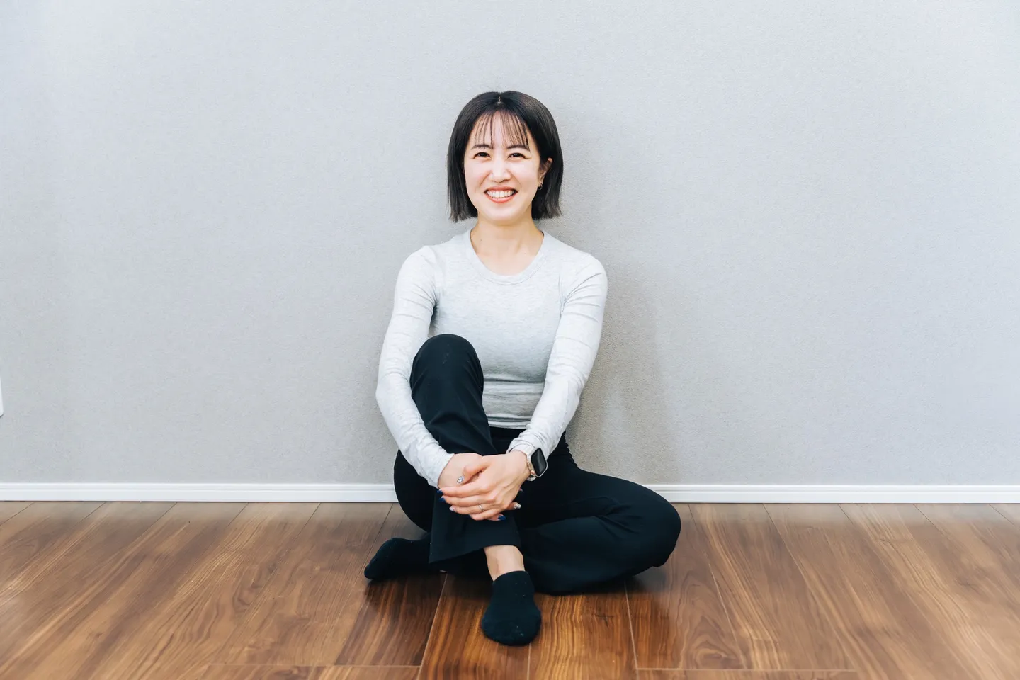 スタジオの床に座って笑っている Yüka Pilates 代表・Yukaさん