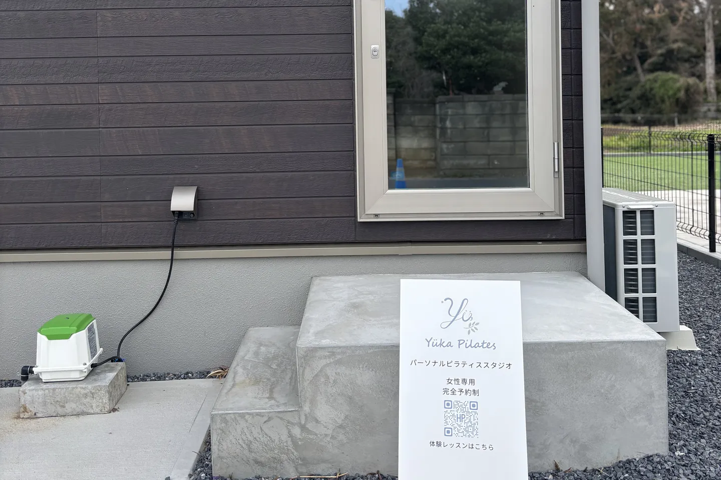 Yüka Pilates のスタジオ専用入口。ガラス扉の手前に、女性専用・完全予約制と書かれた看板が置かれている