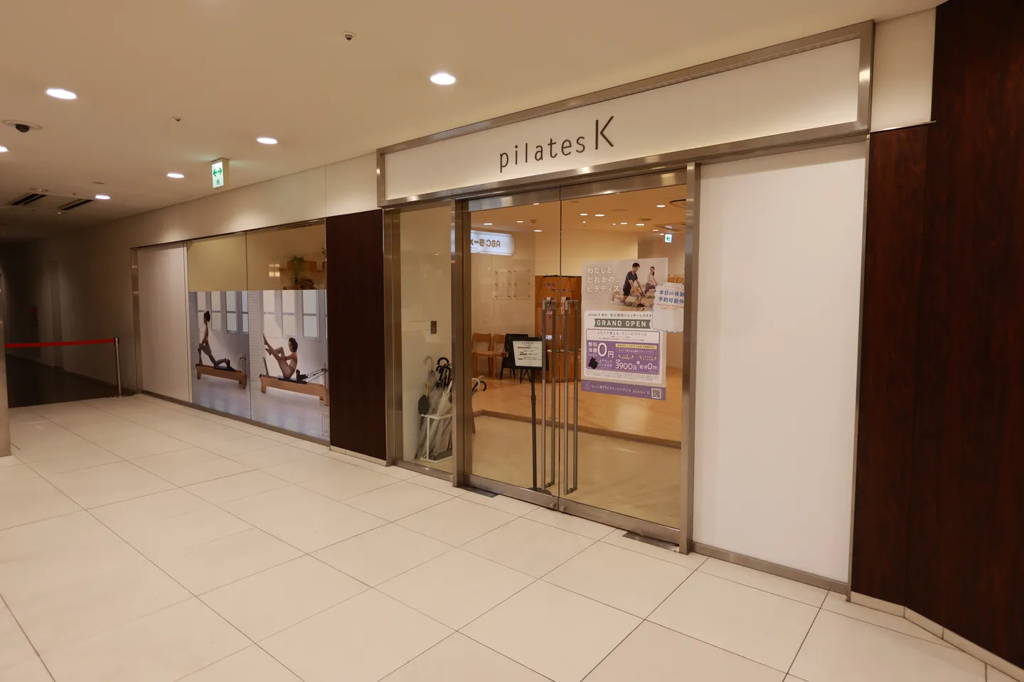 ビルの2階の通路に面した pilates K 中目黒店の入口。ガラス扉の上に pilates K のロゴがある